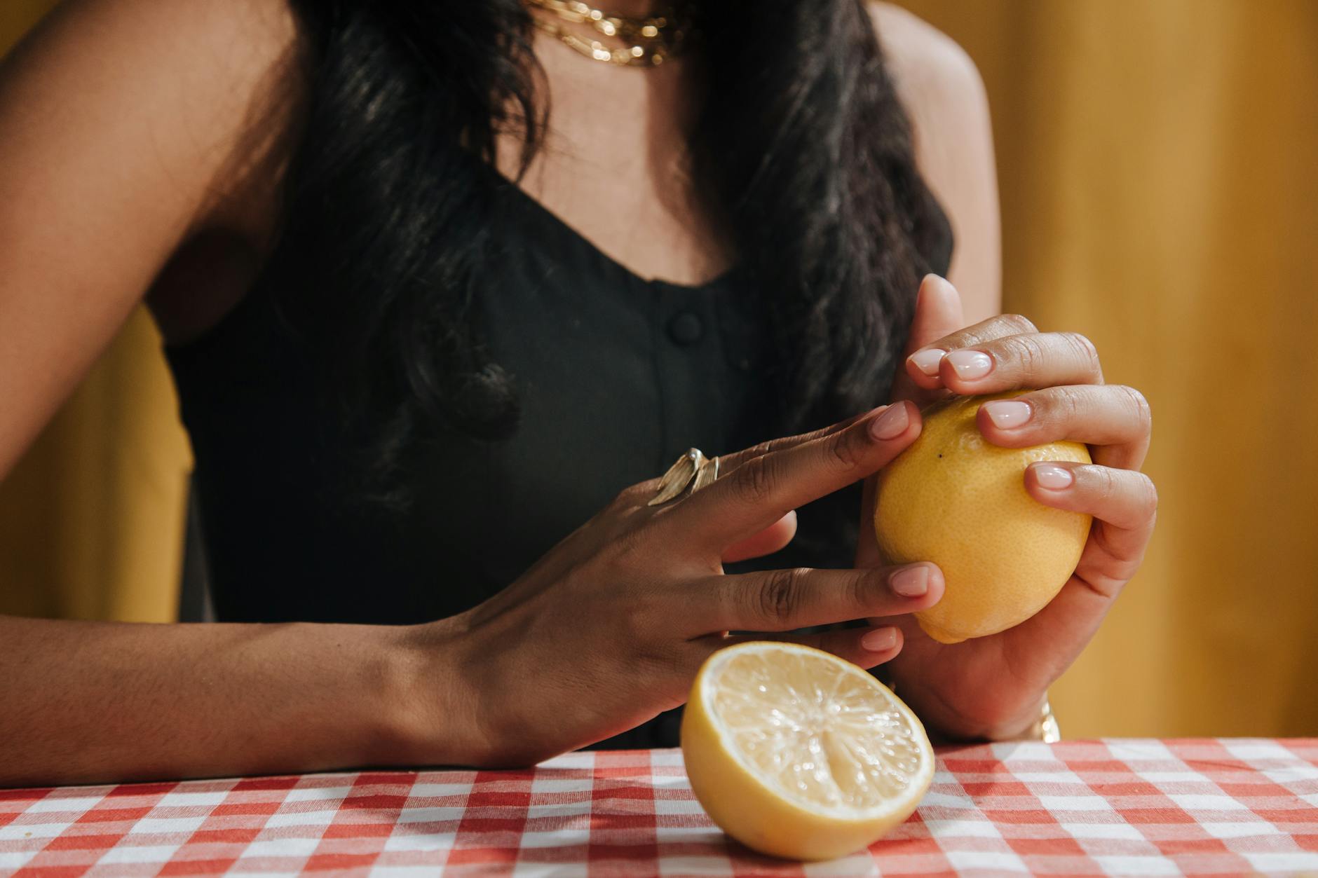 A hand holding a fresh lemon against a bright yellow background, symbolizing the citrus-inspired suction technology of modern clitoral vibrators