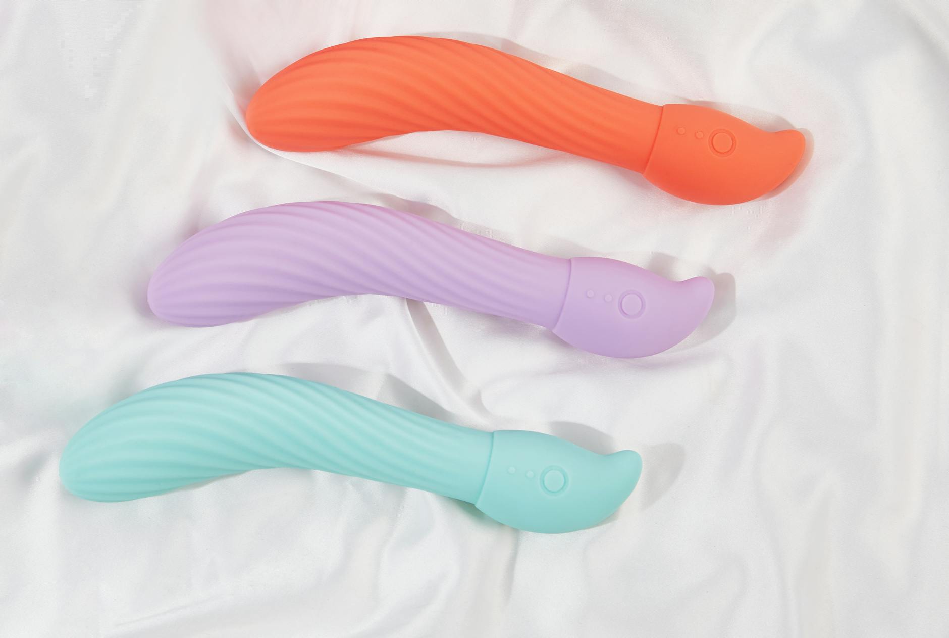 Three colorful vibrators arranged on white fabric, highlighting smooth lemon and wand designs