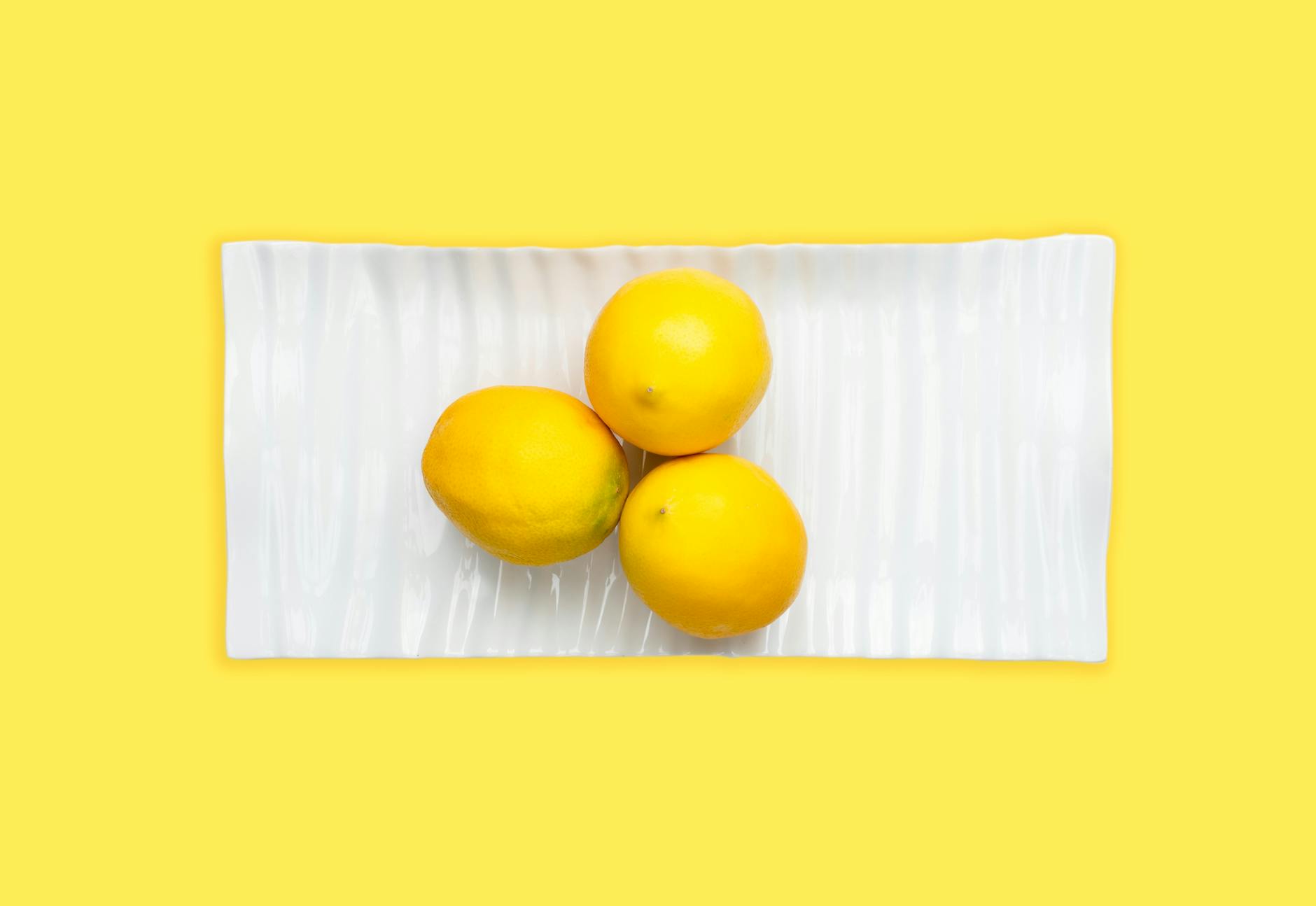 Vibrant collection of adult pleasure toys including lemon vibrators arranged on a bright yellow surface