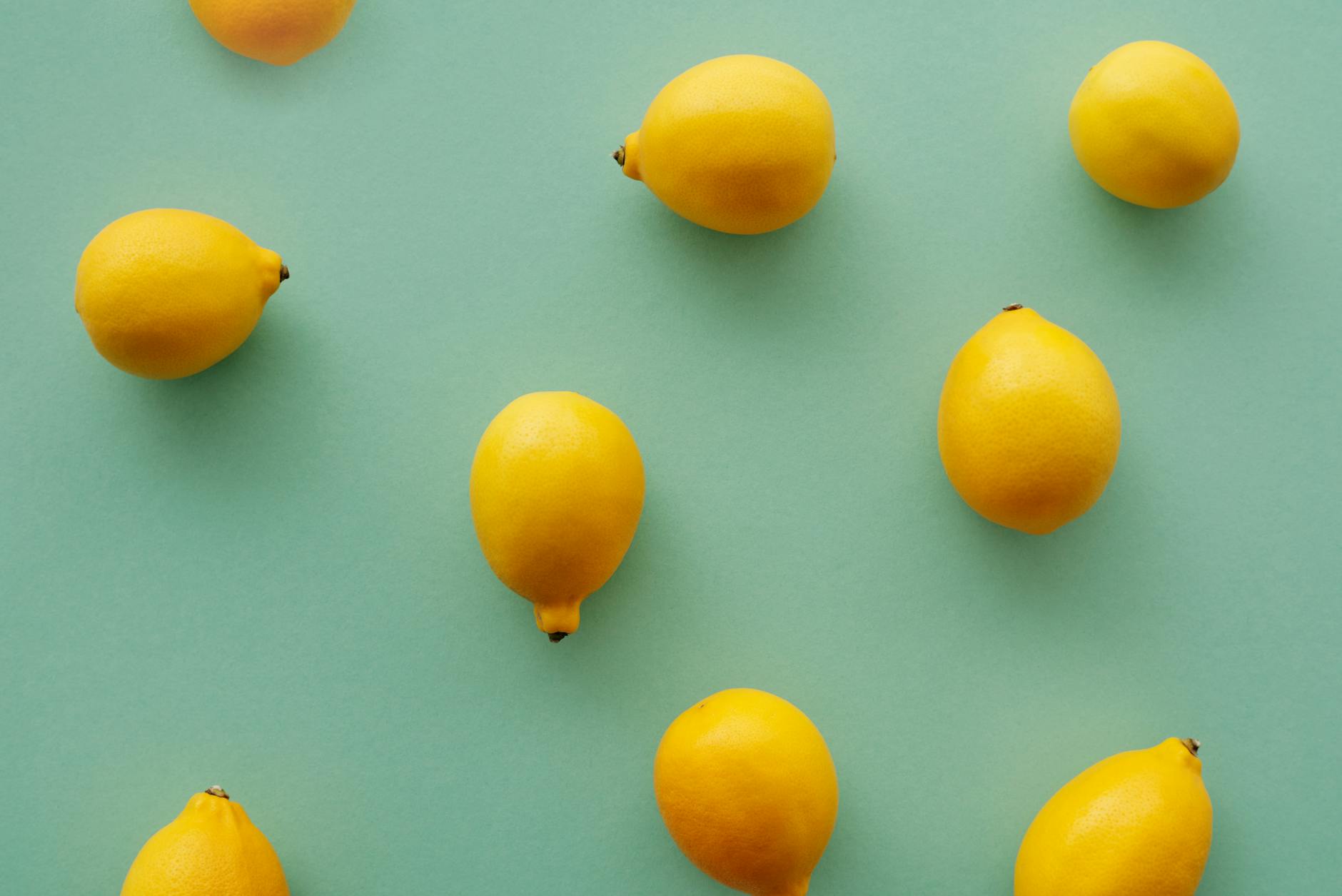 Bright yellow lemons arranged on a pastel green background, representing the Hello Nancy lemon vibrator brand