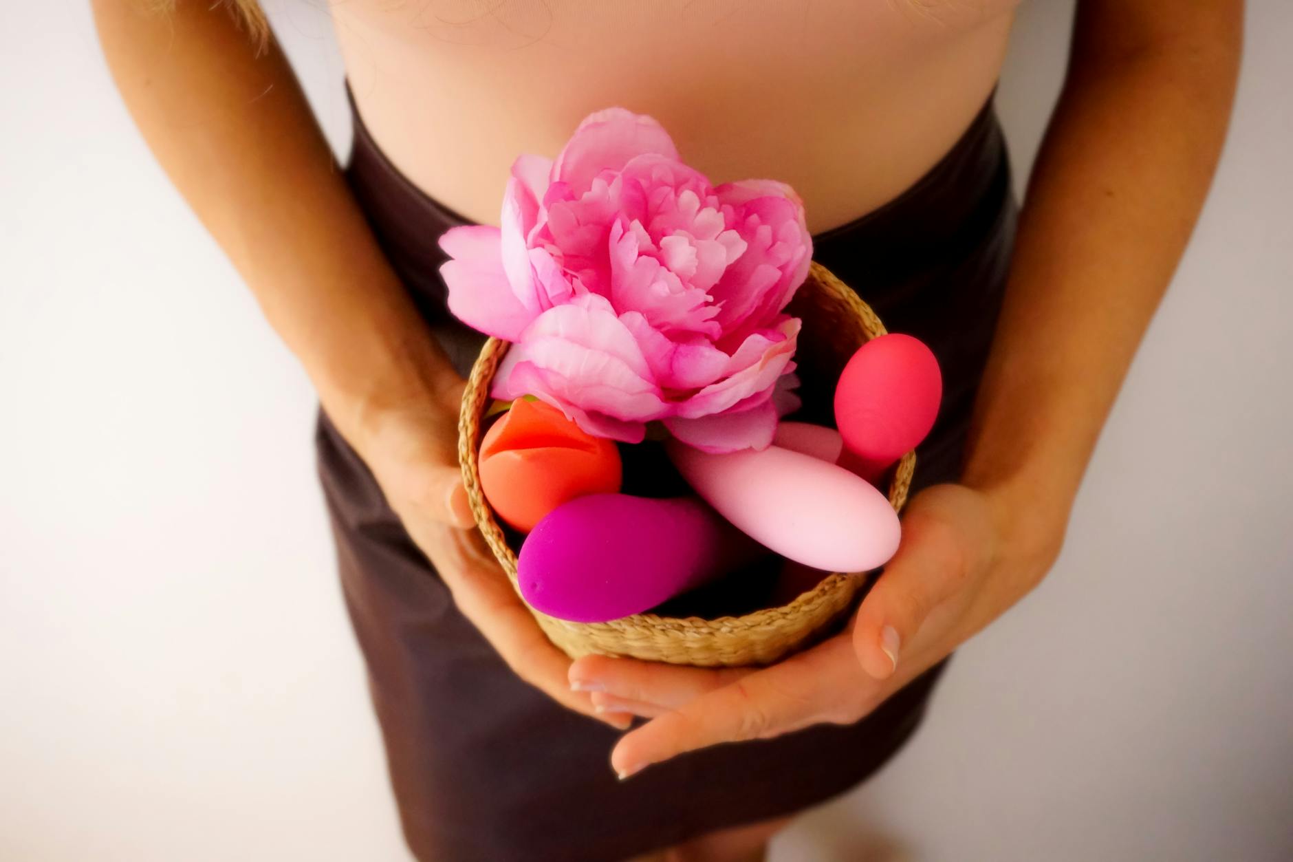 A basket of colorful vibrators and flowers representing pleasure tools and seasonal wellness